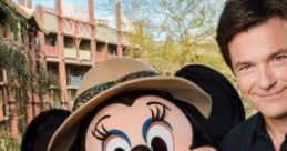 Jason Bateman poses with Minnie Mouse in safari attire, sharing a cheerful moment at a Disney theme park.