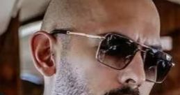 Close-up of a man with a bald head and sunglasses, deep in thought, exuding confidence and style.