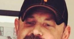 Man with a thick, styled mustache and a baseball cap, exuding a classic redneck style and confident demeanor.