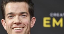 John Mulaney smiles at the Creative Arts Emmys, showcasing his stylish brown suit and bow tie on the red carpet.