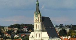 Historic church with a tall spire, surrounded by red rooftops and greenery in a picturesque skyline. Lubor Mrázek's work.