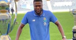 Evan Kindombi Mbemba poses on the field with two prestigious trophies, celebrating his football achievements with Porto.