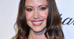 Smiling woman with long wavy hair wearing a stylish dress and a sparkling necklace, exuding elegance and charm.