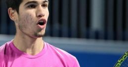 Carlos Alcaraz celebrating a victory on the tennis court, wearing a pink shirt and holding his racquet with enthusiasm.