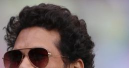 Sachin Tendulkar smiling warmly, wearing sunglasses and a suit, showcasing his iconic personality and charm.