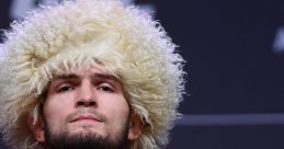 Khabib Nurmagomedov confidently poses in a UFC shirt, showcasing his iconic curly hairstyle before a match.