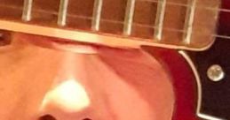 Close-up of Àngel S Guitart’s face viewed through a guitar's sound hole, showcasing musical passion and artistry.