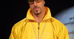 Ali G in a vibrant yellow jacket, oversized sunglasses, and flashy jewelry, embodying comedic style and cultural satire.