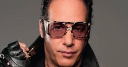 Andrew Dice Clay in a leather jacket with studs, wearing sunglasses, embodying his iconic comedian persona.