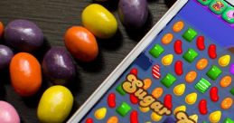 Colorful candies surround a smartphone displaying the Candy Crush game, featuring a high score of 21,450 and vibrant gameplay.