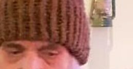 Doug Campbell wearing a brown beanie in front of a grocery store sign, capturing a casual moment in a rustic setting.