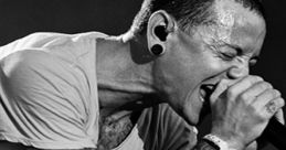 Chester Bennington passionately performing on stage, showcasing his iconic tattoos and intense energy as a Linkin Park frontman.