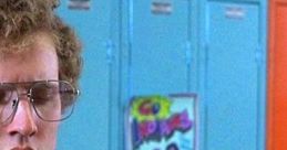 Napoleon Dynamite in college tee stands by colorful lockers, showcasing his iconic awkwardness and style.