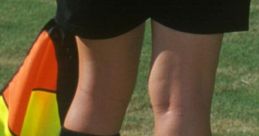 Referee with black socks and skirt, standing on a grassy field, ready to officiate a soccer game, focused and alert.