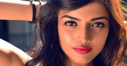 Confident woman with long hair and bold red lips, showcasing her beauty in a stylish tank top against a soft background.