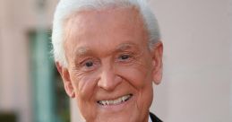 Bob Barker smiles in a formal suit with a red patterned tie, showcasing his iconic television persona.