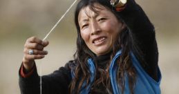 Tibetan woman skillfully spinning yarn with a drop spindle, showcasing traditional textile crafting techniques in natural setting.