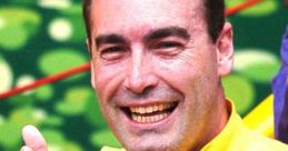 Greg Page smiles and points playfully while wearing a bright yellow shirt, embodying fun and joy for children's entertainment.