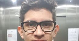 Young man with glasses smiling in an elevator, wearing a lanyard, representing a modern, casual style.