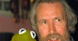 Jim Henson joyfully poses with Kermit the Frog, showcasing the iconic puppet's signature bright green color and playful smile.