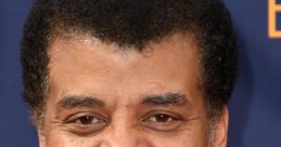 Neil deGrasse Tyson smiling at a red carpet event in a tuxedo with a bow tie, showcasing his charismatic personality.