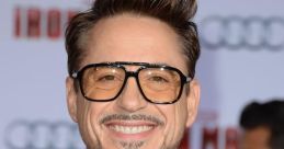 Robert Downey Jr. smiles at the Iron Man premiere, showcasing his stylish suit and signature glasses.