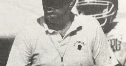 Ben Bernhardt coaching on the field, wearing a Pittsburgh shirt and cap, focused on the game with players in the background.