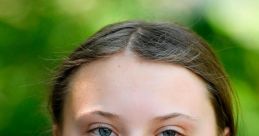 Portrait of Greta Thunberg, young climate activist, with a serene expression against a natural green backdrop.