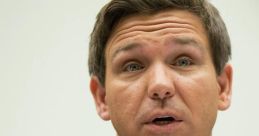 Ron DeSantis speaking at a congressional hearing, expressing strong opinions on key policy issues, wearing a suit and tie.