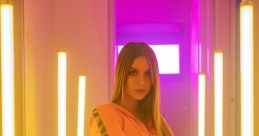 Young woman in vibrant pink tracksuit posing confidently amidst neon lights, showcasing a stylish and modern aesthetic.