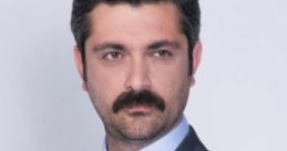 Oktay Gurcay in a tailored gray suit, showcasing his distinctive mustache and confident expression, perfect for promotional use.