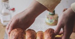 Freshly baked bread being handled with care on a wooden board, surrounded by flowers and rustic kitchen items.