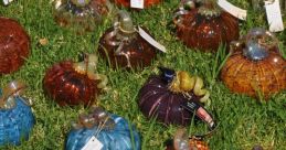 Colorful glass pumpkins in various shapes and tones displayed on grass, perfect for autumn decor and seasonal celebrations.