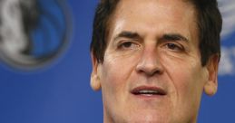 Mark Cuban speaking at a Dallas Mavericks press conference, wearing a team polo and showcasing team spirit.