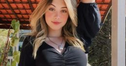 Stylish young woman in black crop top and gray sweatpants posing on a balcony, showcasing a trendy casual look.