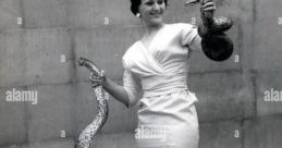 Woman in stylish dress holding snakes, showcasing charisma and beauty, reminiscent of Alba Julieth Méndez Suárez's elegance.