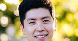 Portrait of Yang Hoon Cho, smiling confidently in a suit, with a bright, blurred background of nature.