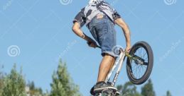 BMX rider performing an impressive jump against a clear blue sky, showcasing extreme sports skills and agility.