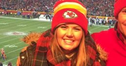 Cheerful fan at a football game, wearing a Chiefs hat, celebrating the excitement of the sport and family ties.