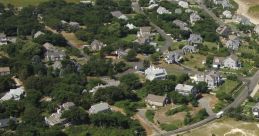 Aerial view of the Dennis Club area, featuring residences, a tennis court, and a marina with boats. Ideal for coastal recreation.