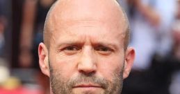 Jason Statham in a stylish gray suit and tie, exuding confidence at a red carpet event. Hollywood actor's striking presence.