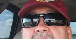 Alfredo Loya wearing sunglasses and a maroon cap with a logo, capturing a casual moment inside a vehicle.