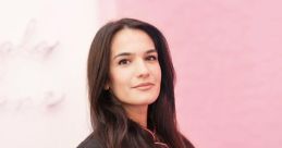 Martina Camarasa Carbonell posing confidently in a stylish black uniform with pink accents, set against a vibrant pink backdrop.