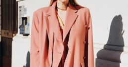 Chic fashionista in a pink oversized blazer, layered dress, and stylish accessories, showcasing vibrant trend-setting style.