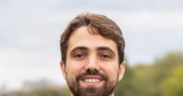 Guilherme Silveira smiling outdoors, wearing a gray blazer and white shirt, with a blurred natural background.