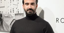 Ayman Hafidi poses confidently against a minimalist backdrop, showcasing a stylish black turtleneck sweater.