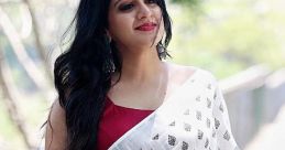 Akhila Chavan radiates elegance in a white saree with intricate patterns, enjoying a sunny day outdoors.