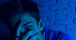 Young man with blue lighting covering half his face, wearing a purple sweatshirt and accessories, expressing a mysterious vibe.