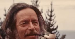 Alan Watts smiling outdoors, sporting a pipe, colorful tie, and stylish shirt, surrounded by lush greenery.