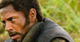 Character from Tropic Thunder, showcasing intense emotions and survival in a tough, wilderness setting.